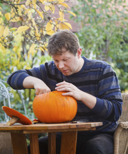 Man carving pumpkin alone