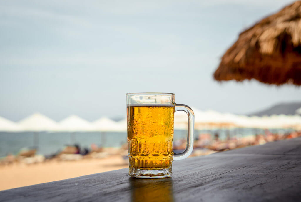 Mug of cold beer during summer on beach