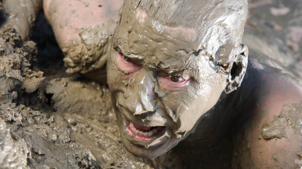 Naked man covered in mud