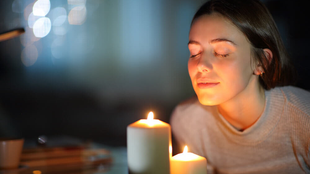Woman smelling a lighted candle in the night